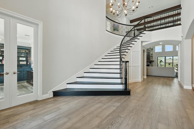 3905 Dashiell Dr, Flower Mound, TX 75022 - stairs featuring arched walkways, a chandelier, wood finished floors, a towering ceiling, and baseboards