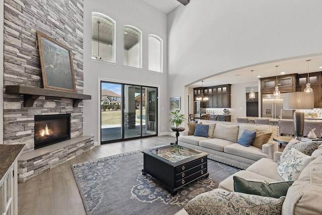 3905 Dashiell Dr, Flower Mound, TX 75022 - living area with wood finished floors, a high ceiling, a stone fireplace, and arched walkways
