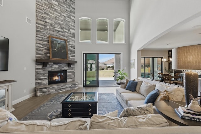 3905 Dashiell Dr, Flower Mound, TX 75022 - living room with wood finished floors, a fireplace, a towering ceiling, a chandelier, and baseboards