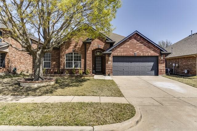 traditional home with central air condition unit, a garage, brick siding, and concrete driveway