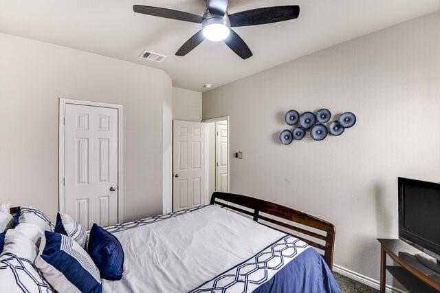 carpeted bedroom featuring baseboards, ceiling fan, and visible vents