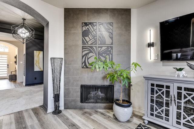 interior space with arched walkways, a fireplace, and wood finished floors