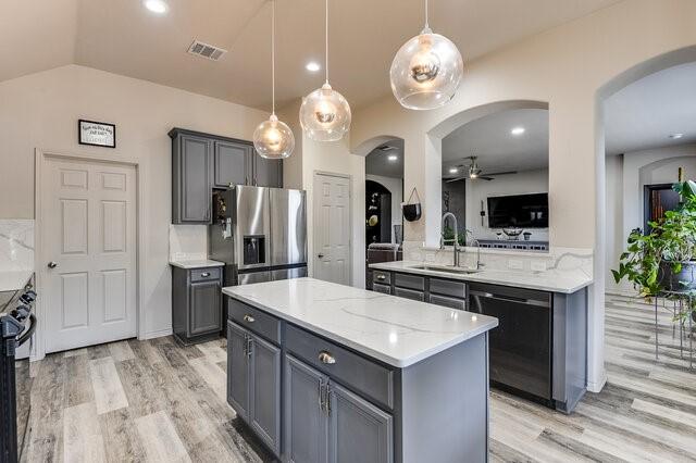 kitchen featuring arched walkways, dishwashing machine, a sink, and stainless steel refrigerator with ice dispenser