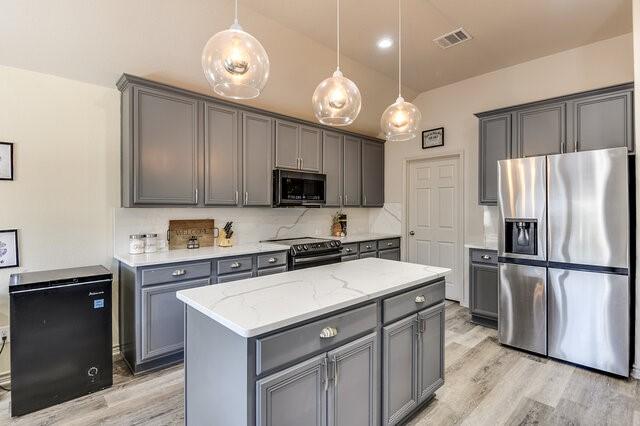 kitchen featuring visible vents, stainless steel appliances, light wood-style floors, light stone counters, and gray cabinets