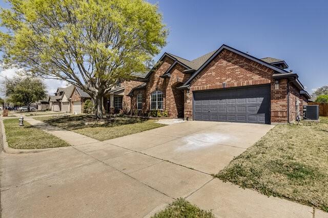 view of front of property featuring central AC, a garage, brick siding, and concrete driveway