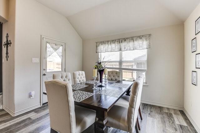 dining room with baseboards, lofted ceiling, and wood finished floors