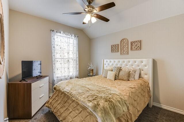 carpeted bedroom with baseboards, ceiling fan, and vaulted ceiling