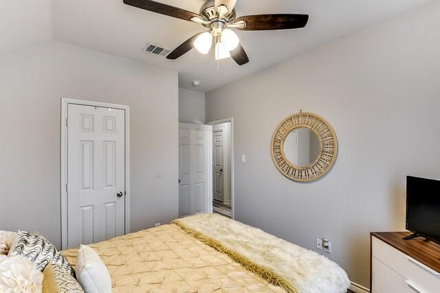 bedroom with vaulted ceiling, visible vents, and a ceiling fan