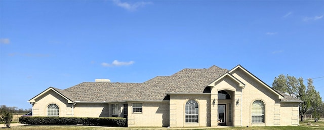 view of front of home with a chimney, a shingled roof, brick siding, and a front yard