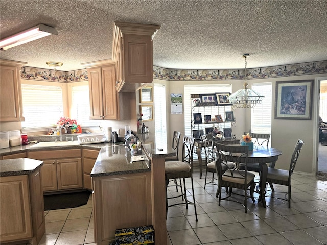 kitchen featuring a kitchen breakfast bar, a textured ceiling, a sink, a peninsula, and a notable chandelier