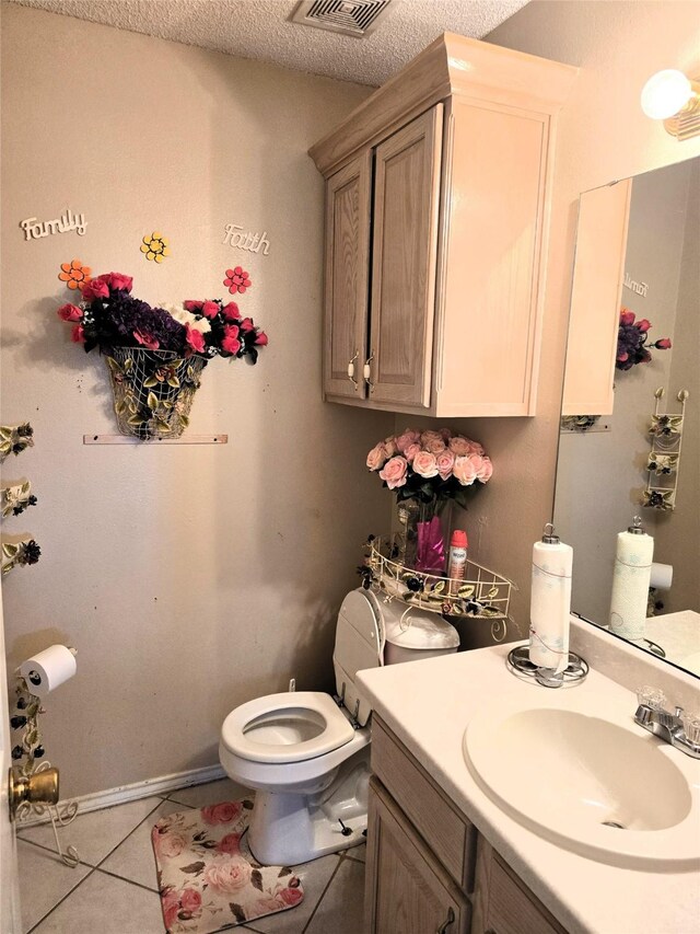bathroom with a textured ceiling, visible vents, toilet, tile patterned floors, and vanity