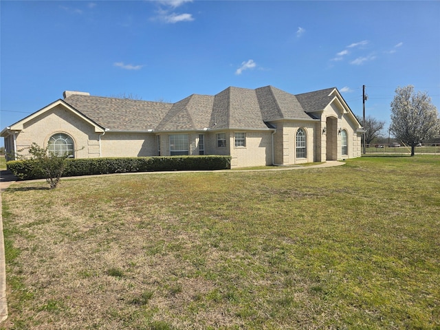 view of front of property featuring brick siding, a shingled roof, and a front yard