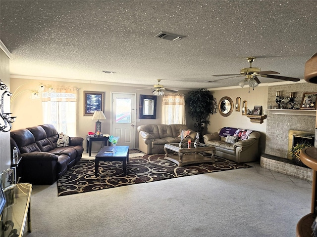 carpeted living room with a brick fireplace, visible vents, a textured ceiling, and ceiling fan