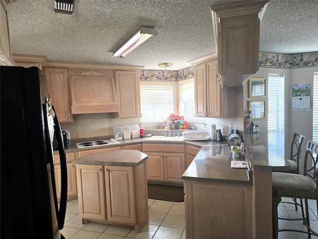 kitchen featuring black fridge with ice dispenser, light brown cabinetry, premium range hood, a peninsula, and white cooktop