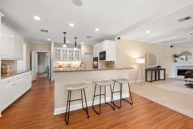 2034 Oak Glen Dr, Mcgregor, TX 76657 - kitchen featuring black appliances, a kitchen bar, white cabinets, open floor plan, and glass insert cabinets