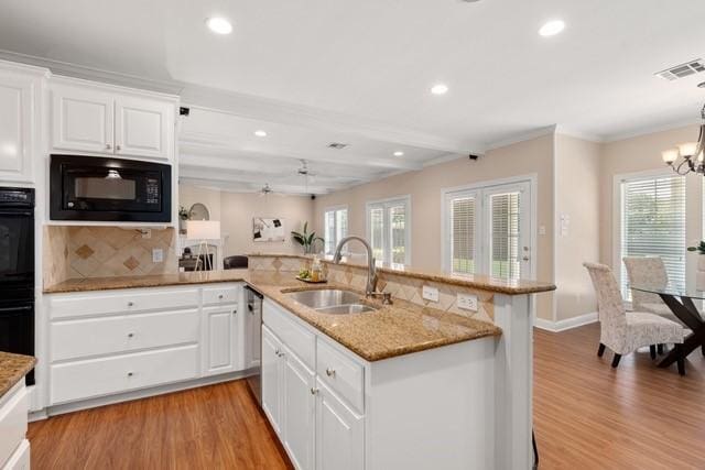 2034 Oak Glen Dr, Mcgregor, TX 76657 - kitchen with a sink, black appliances, light wood-type flooring, recessed lighting, and a chandelier