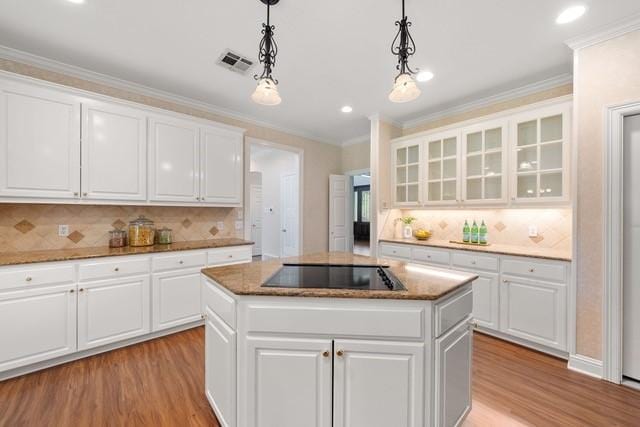 2034 Oak Glen Dr, Mcgregor, TX 76657 - kitchen with black electric stovetop, light wood-style floors, a kitchen island, crown molding, and tasteful backsplash