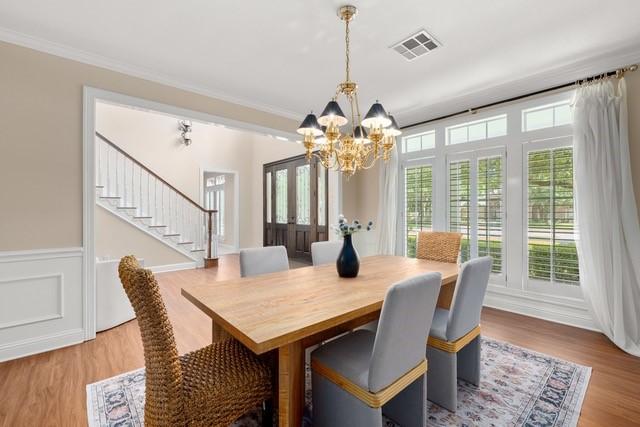 2034 Oak Glen Dr, Mcgregor, TX 76657 - dining room featuring a chandelier, stairway, wood finished floors, a wainscoted wall, and ornamental molding