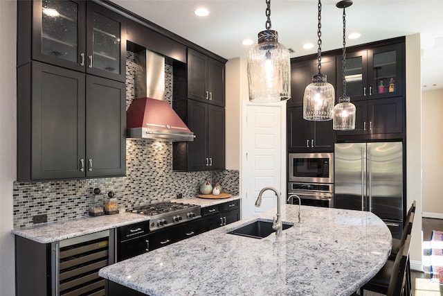 3703 Panalero Ln, Dallas, TX 75209 - kitchen with wine cooler, a sink, built in appliances, wall chimney exhaust hood, and backsplash