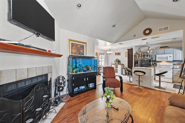 3217 Whatley Dr, Garland, TX 75043 - living room with lofted ceiling, light wood-style flooring, a fireplace, and a chandelier
