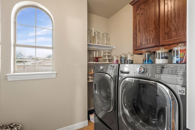 laundry area with baseboards, washing machine and dryer, and cabinet space