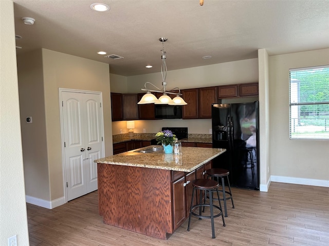 kitchen featuring baseboards, light wood-style floors, black appliances, and visible vents