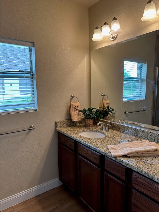 full bath featuring vanity, baseboards, and wood finished floors