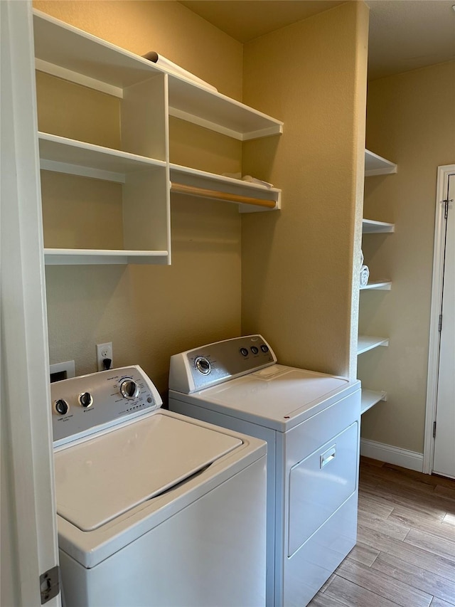 laundry area with baseboards, laundry area, washer and clothes dryer, and light wood finished floors