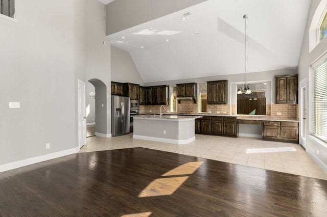 7813 Saint Clair Dr, Mckinney, TX 75071 - kitchen with light countertops, dark brown cabinets, appliances with stainless steel finishes, arched walkways, and an island with sink