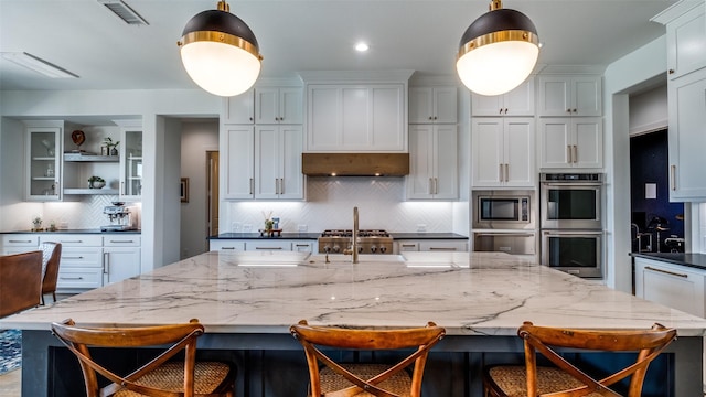 6023 Manderlay Dr, Frisco, TX 75034 - kitchen featuring stainless steel appliances, backsplash, a warming drawer, an island with sink, and a kitchen bar