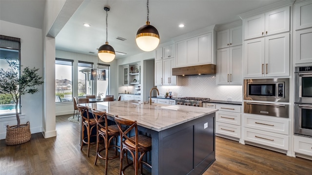 6023 Manderlay Dr, Frisco, TX 75034 - kitchen with a warming drawer, appliances with stainless steel finishes, a sink, dark wood-type flooring, and a kitchen breakfast bar
