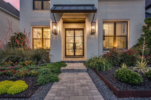 6023 Manderlay Dr, Frisco, TX 75034 - exterior entry at dusk featuring brick siding, a standing seam roof, and metal roof