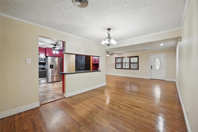 unfurnished living room with light wood-style floors, ceiling fan with notable chandelier, ornamental molding, and visible vents