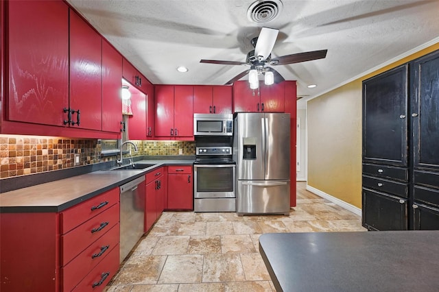 kitchen featuring red cabinetry, appliances with stainless steel finishes, decorative backsplash, and a sink