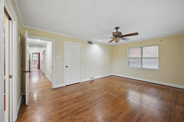unfurnished room featuring a wealth of natural light, visible vents, wood finished floors, and ceiling fan