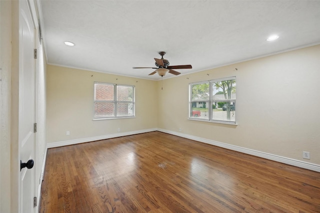 spare room with a wealth of natural light, baseboards, wood finished floors, and ceiling fan