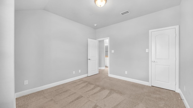 unfurnished bedroom with carpet flooring, visible vents, baseboards, and vaulted ceiling