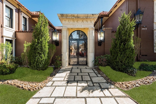 property entrance with french doors, a tiled roof, and stucco siding