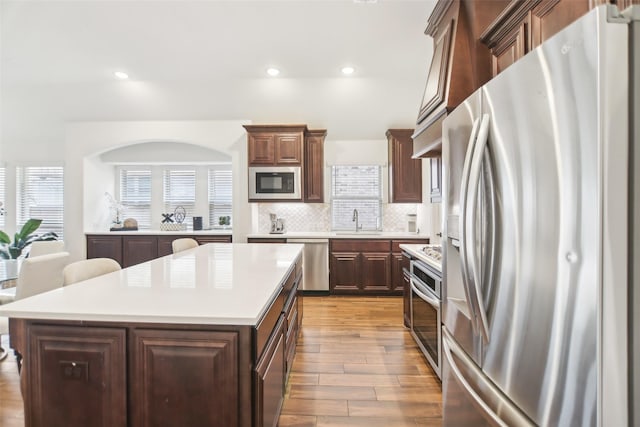 1236 Arrowwood Dr, Aubrey, TX 76227 - kitchen with light countertops, wood finished floors, tasteful backsplash, appliances with stainless steel finishes, and a sink