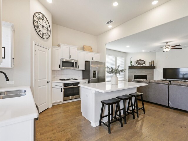 5024 Wilder Ave, Celina, TX 76227 - kitchen with appliances with stainless steel finishes, a sink, a center island, a fireplace, and a kitchen bar