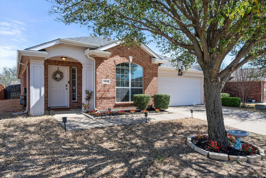 ranch-style house featuring driveway, brick siding, and an attached garage