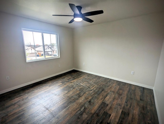 empty room featuring baseboards, dark wood-style floors, and a ceiling fan