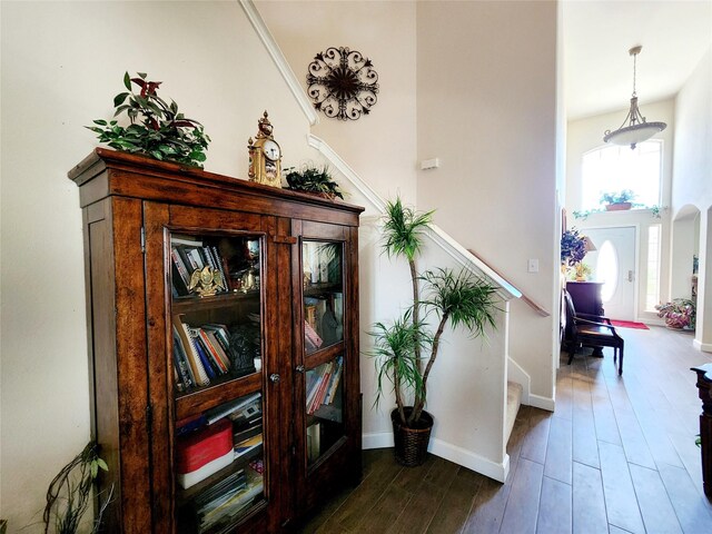 hallway with stairs, baseboards, and dark wood-type flooring