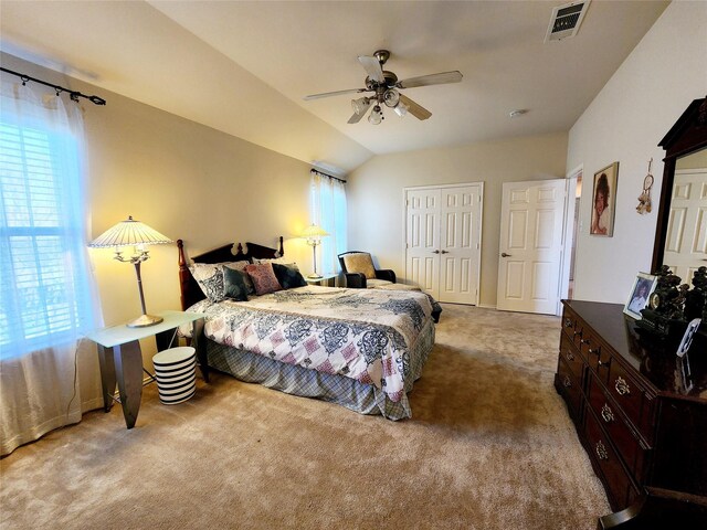 carpeted bedroom with lofted ceiling, visible vents, ceiling fan, and a closet