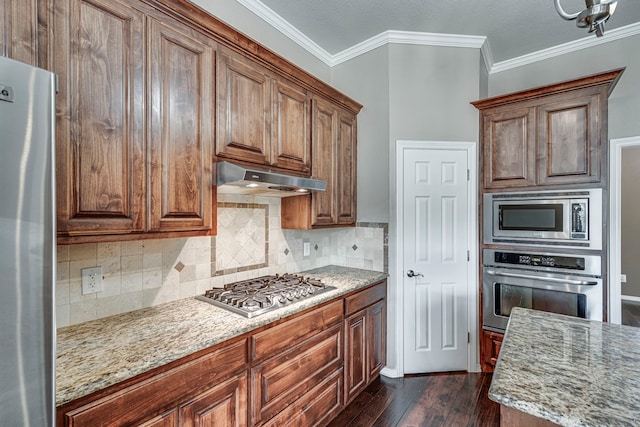 5440 Sycamore Dr, Midlothian, TX 76065 - kitchen with appliances with stainless steel finishes, under cabinet range hood, dark wood-type flooring, ornamental molding, and light stone counters
