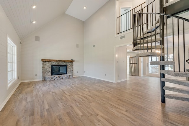 unfurnished living room with stairs, a fireplace, visible vents, and wood finished floors