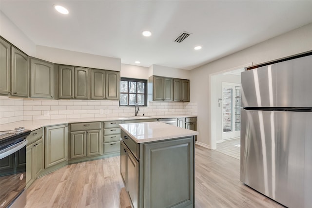 kitchen featuring light countertops, visible vents, light wood finished floors, appliances with stainless steel finishes, and a sink