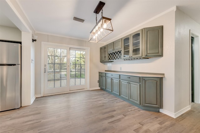 kitchen featuring freestanding refrigerator, green cabinetry, light wood-style floors, and visible vents
