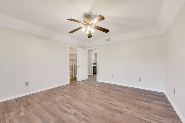 empty room featuring a ceiling fan, baseboards, light wood finished floors, and visible vents