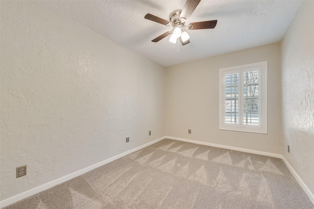 spare room featuring a ceiling fan, a textured wall, and carpet